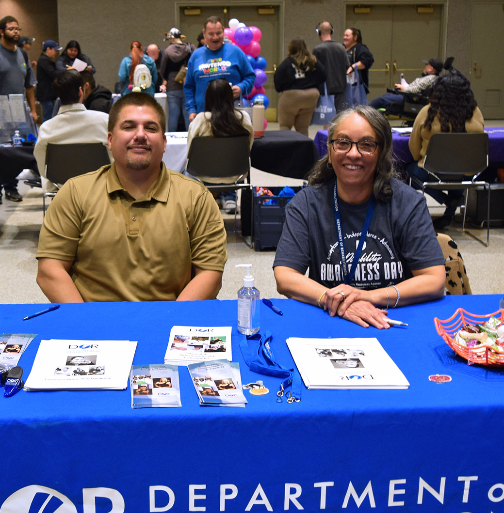 Photo of a vendor table at 2024 Disability Awareness Day with a man and woman smiling and representing the California Department of Rehabilitation.