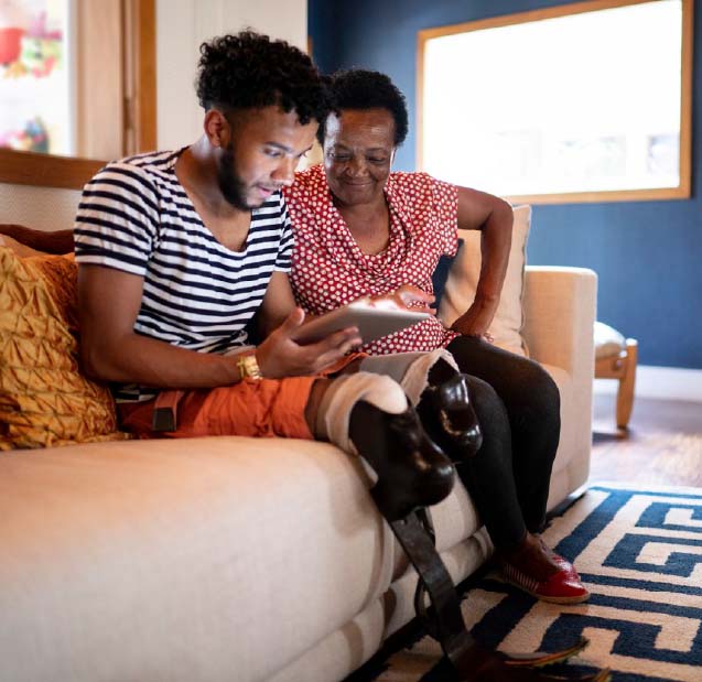 Photo of a young man showing a digital tablet to his grandmother.